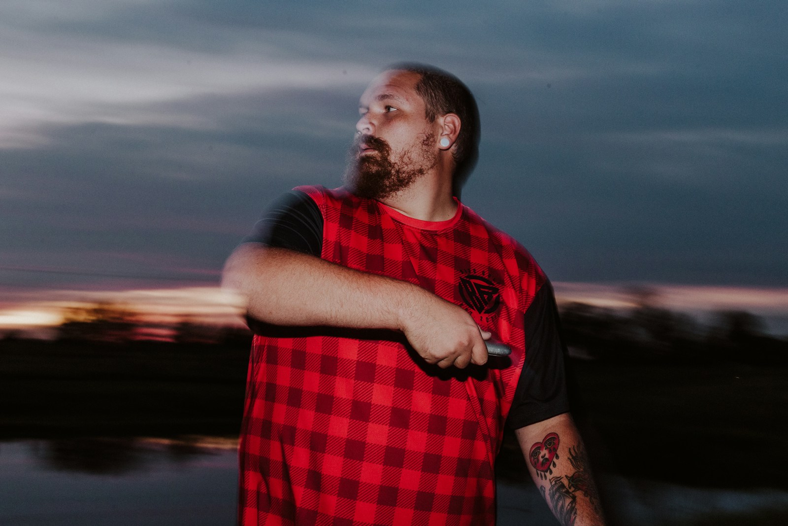 A man in a red and black shirt is holding a knife